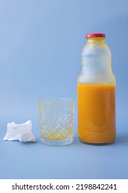On a blue background, a close-up of an empty dirty glass of orange pumpkin juice top view next to a napkin and a bottle