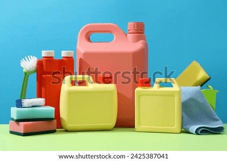 On a blue background, colorful empty canisters decorated with cleaning equipments. Plastic canisters mockup for design packaging. Front view, advertising photo for professional cleaning service