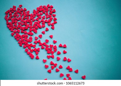 On a blue background a large red heart splits into pieces. Unhappy love, unrequited feelings, disappointment. Vignetting, copy space.