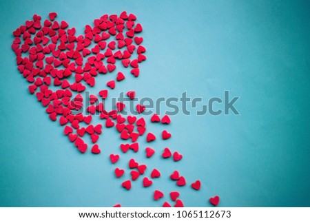 On a blue background a large red heart splits into pieces. Unhappy love, unrequited feelings, disappointment. Vignetting, copy space.