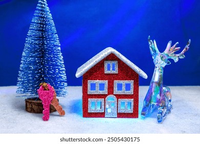 On a blue background, a red house with blue light in the windows, surrounded by keys, a blue Christmas tree and a deer figurine - Powered by Shutterstock