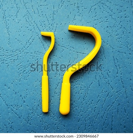 on a blue background are two plastic hooks of different sizes to remove ticks from dogs