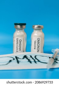 On A Blue Background, Two Vials Containing A Vaccine From The New Covid-19 Omicron Variety, A Medical Mask, And A Syringe