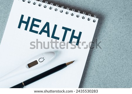 On blue surface a white notepad with word HEALTH, a black pen and a thermometre on it.