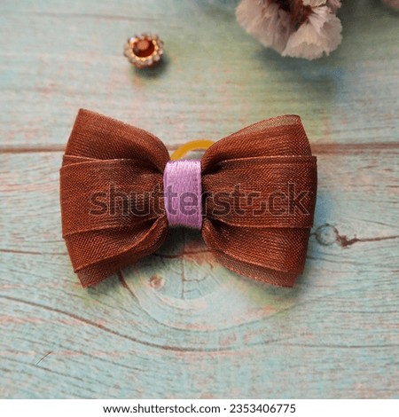 on a blue wooden table a brown bow with a purple ribbon in the middle. hair accessories . bow