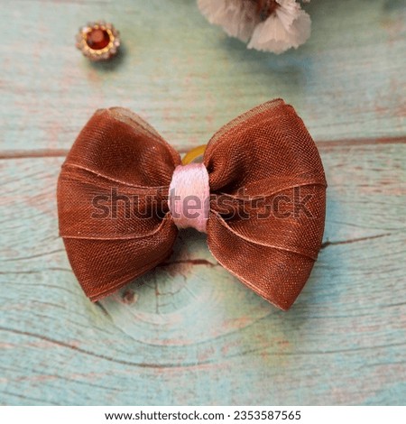 on a blue wooden table a brown bow with a pink ribbon in the middle. view from above . hair accessories . bow
