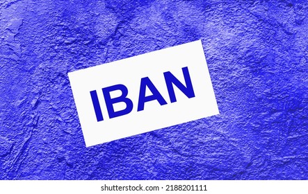 On A Bright Blue Abstract Background, There Is A White Card With The Text IBAN International Bank Account Number