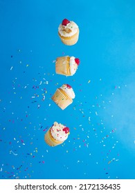 On A Bright Blue Background, Small Muffins With Cream And Raspberries In Free Flight. Treats For A Holiday, Birthday, Banquet, Picnic. There Are No People In The Photo. Banner, Advertising.