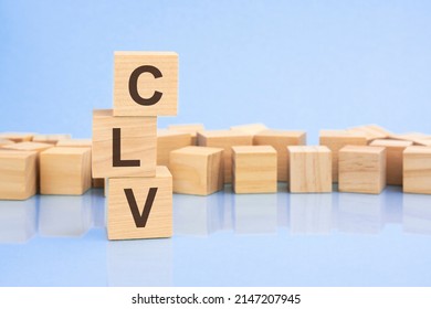 on a bright pale lilac and blue background, light wooden blocks and cubes with the text CLV. cubes is reflected from the surface. CLV - means Customer Lifetime Value