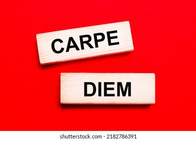 On a bright red background, there are two light wooden blocks with the text CARPE DIEM