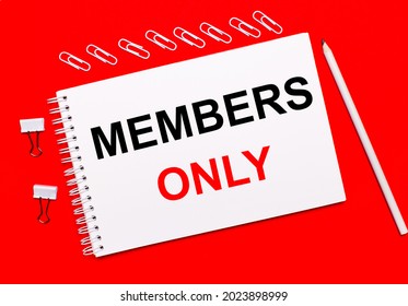 On A Bright Red Background, A White Pencil, White Paper Clips, And A White Notebook With The Text MEMBERS ONLY.