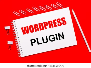 On a bright red background, a white pencil, white paper clips, and a white notebook with the text WORDPRESS PLUGIN