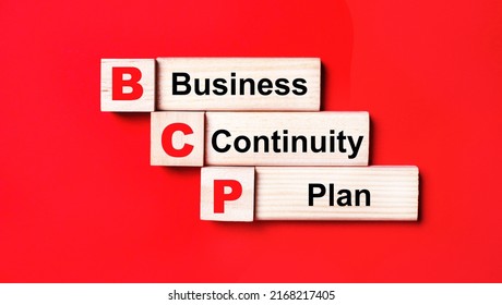 On a bright red background, wooden cubes and blocks with the text BCP Business Continuity Plan. Manufacturing of wooden toys. - Shutterstock ID 2168217405