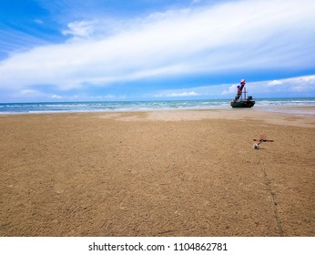 On Bright Sunny Day With Beautiful Sky, A Local Fishing Boats Aground And Waiting For The Rising Tide With Anchor Of The Other Boat As Foreground.