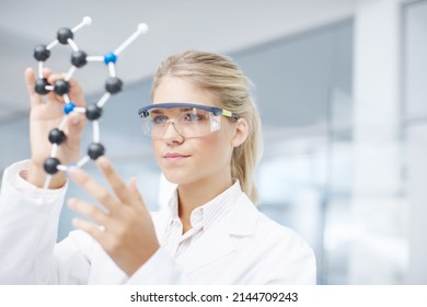 On the brink of a medical break-through. A gorgeous young scientist looking at a molecular structure model. - Powered by Shutterstock