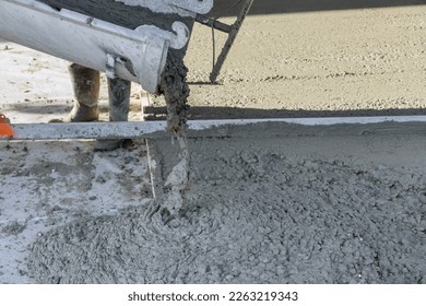 On building site concrete mixing truck is pouring concrete for pavement surrounding newly constructed home