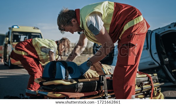 On the Car Crash Traffic Accident Scene:\
Paramedics and Firefighters Rescue Injured Victim Trapped in the\
Vehicle. Extricate Person Using Stretchers, Give First Aid and\
Transport Them to Hospital