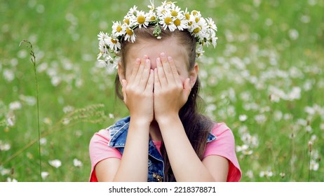 On A Chamomile Lawn, A Sweet Girl In A Wreath Of Daisies, Smiling, Pressing Her Hands To Her Cheeks. High Quality Photo