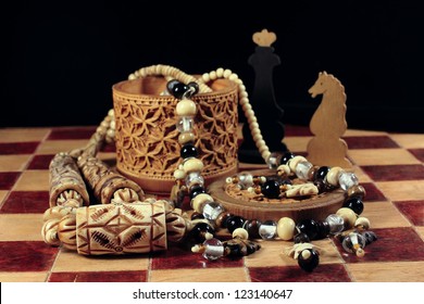 On a chessboard there is a casket from birch bark and a beads from an ivory and handmade chessman