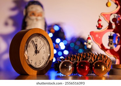 On Christmas Eve, there is a clock, a pine cone, Santa, Christmas tree decorations, Christmas lights and a tabletop Christmas tree on the table. - Powered by Shutterstock