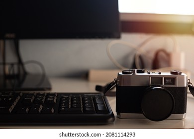 on the computer desk There was an old camera next to it;desk with camera There was light coming from the window.
