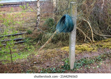 On A Concrete Fence Post Hangs A Roll Of Winding Wire