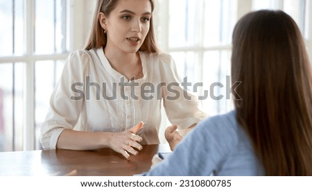 On consultation. Sincere attentive female psychologist helping solve problems discussing life situation with young woman client, bank consultant or sales manager giving advices to interested customer ストックフォト © 