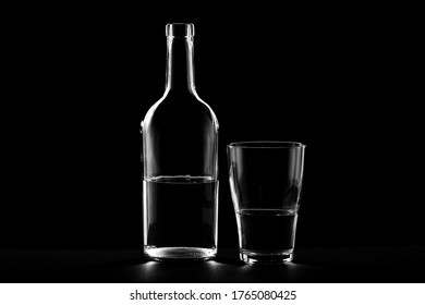 on a dark background, the bottle and glass are outlined. glare on the walls of the bottle and drinking tank