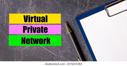 On a dark marble background, a tablet with paper, pen and three bright multi-colored strips of paper with the text VPN Virtual Private Network
