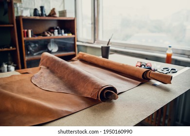 On a daylit table by the window in a shoe shop are rolls of leather for boot production - Powered by Shutterstock