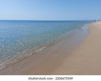 On The Deserted Beach You See Only One Person Walking In The Distance. The Sea Is Beautiful, Quiet, And The Water Is Shallow And Transparent. An Image Of Peace And Serenity. 