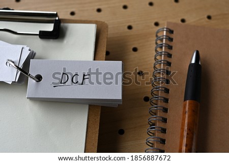 On the desk there is a clipboard, a notebook, and a word book with the word DCF written on it. It was an abbreviation for discounted cash flow.