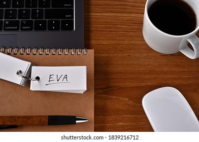 On The Desk There Is A Laptop, A Cup Of Coffee, And A Word Book With The Word EVA Written On It. It Was An Abbreviation For Economic Value Added.