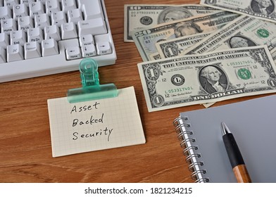 On The Desk Were Bills, A Keyboard, And Memos With The Word Asset Backed Security Written On It.