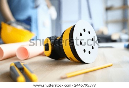 On desktop lies builder tool and sander machine. Tool is used for polishing and grinding surfaces wood. Preliminary cleaning and polishing surfaces. Creates comfortable repair conditions