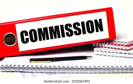 On the desktop are notebooks, a pen and a red folder for papers with the text COMMISSION. Business concept - Shutterstock ID 2210367493