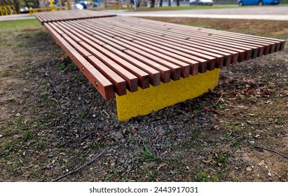 on the edge of the elevated terrace overlooking the park is a concrete long flowerpot with wood paneling and a rectangular bench. is part of the city promenade on the street and square