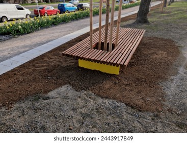 on the edge of the elevated terrace overlooking the park is a concrete long flowerpot with wood paneling and a rectangular bench. is part of the city promenade on the street and square