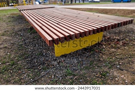 on the edge of the elevated terrace overlooking the park is a concrete long flowerpot with wood paneling and a rectangular bench. is part of the city promenade on the street and square
