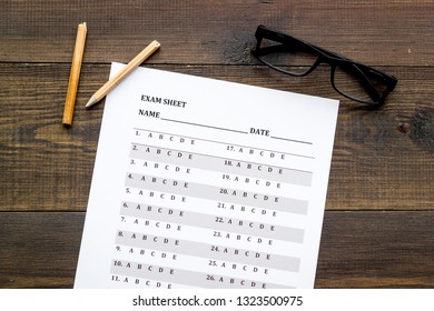 On the exam. Exam sheet, answer near glasses and pencil on dark wooden background top view