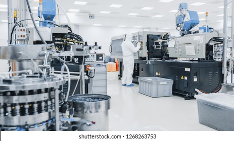 On A Factory Scientist In Sterile Protective Clothing Work On A Modern Industrial 3D Printing Machinery. Pharmaceutical, Biotechnological And Semiconductor Manufacturing Process Shot From Inside.