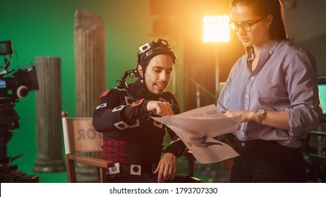 On Film Set: Prominent Female Director Explains Scene To Male Actor Wearing Motion Capture Suit And Playing Green Screen Scene In Superhero Movie. On Big Film Studio Professional Crew