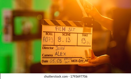 On Film Studio Set Young Camera Assistant Holds Clapperboard with Written Information on it. In the Background Director Shooting Green Screen Scene. History Costume Drama Movie. Close up Shot.
