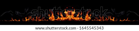 On fire flames at the black background, Burning red hot sparks rise, Fiery orange glowing flying particles