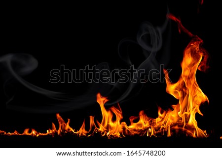 On fire flames at the black background, Burning red hot sparks rise, Fiery orange glowing flying particles