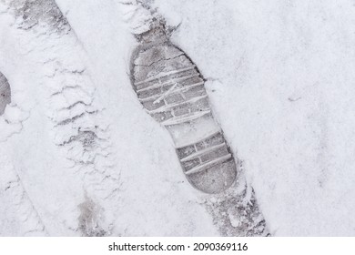 on fresh snow, an imprint of the soles of winter shoes with a transverse pattern providing safe walks on snow-covered and icy surfaces, selective focus - Shutterstock ID 2090369116