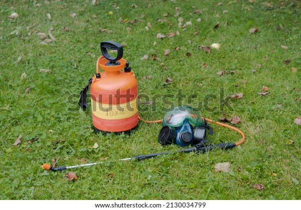 On grass there is sprayer with inscription\
toxic, next to it lies respirator for respiratory protection,\
glasses for eye protection. Disinsection and treatment of plots,\
houses against pests,\
termites