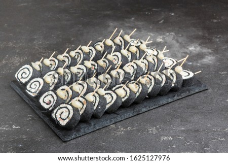 On a gray background is a gray graphite Board, on the Board a lot of cold snacks, sandwiches, canapes, sandwiches for the holiday. Bread, eggs, meat, fish, vegetables, greens, catering.