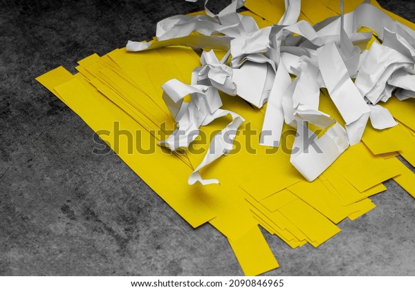 on a gray\
background, white crumpled and yellow smooth paper clippings; the\
problem of paper waste\
recycling