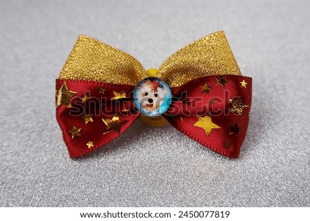 On a gray shiny background there is a red bow with stars with glued rhinestones and an insert in the middle with a white dog. accessories for pets. Top notes for long hair on the head. front view